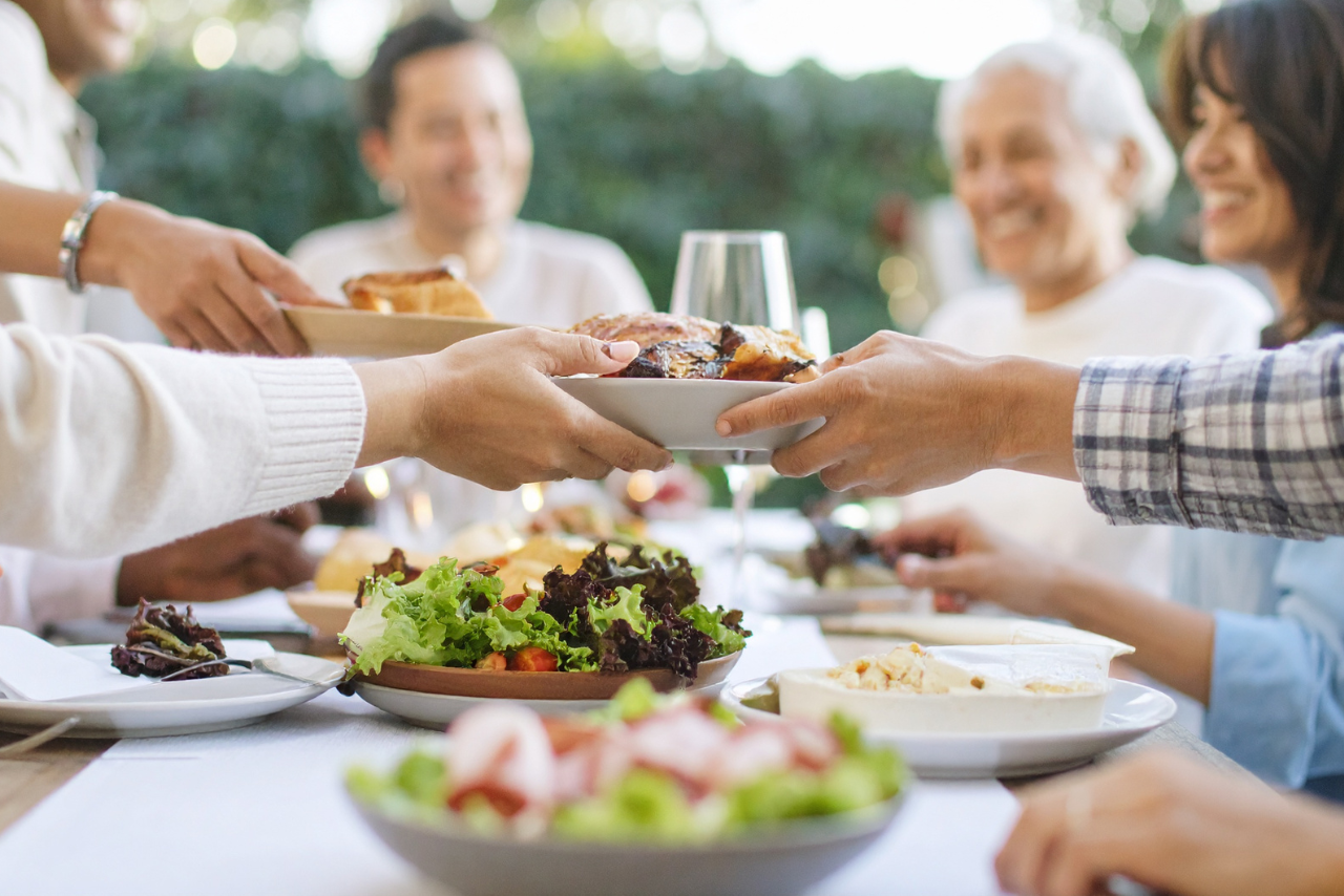 Family passing dishes at an outdoor dinner gathering